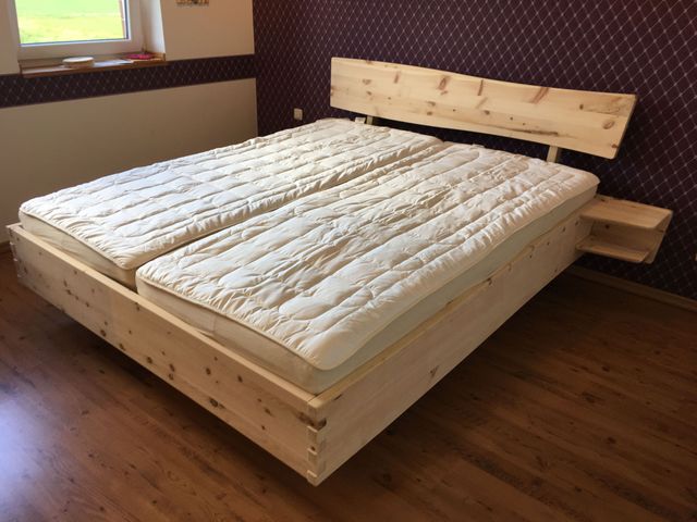 Zirbendoppelbett mit Fingerzinken am Fußteil und einem Geschwungenen Kopfteil mit Luft zur Matratze. 