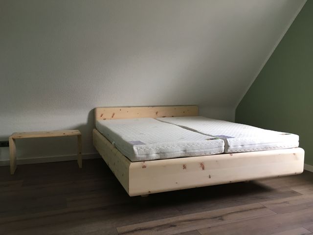 Zirbendoppelbett in Dachschräge, mit einem Beistelltisch.