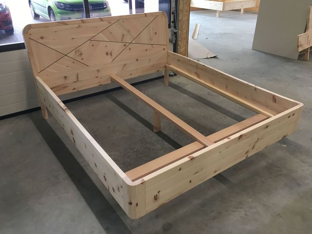 Zirbenbettgestell in Werkstatt, mit einem Kopfteil wo Lisenen aus Nussbaum eingearbeitet sind. 